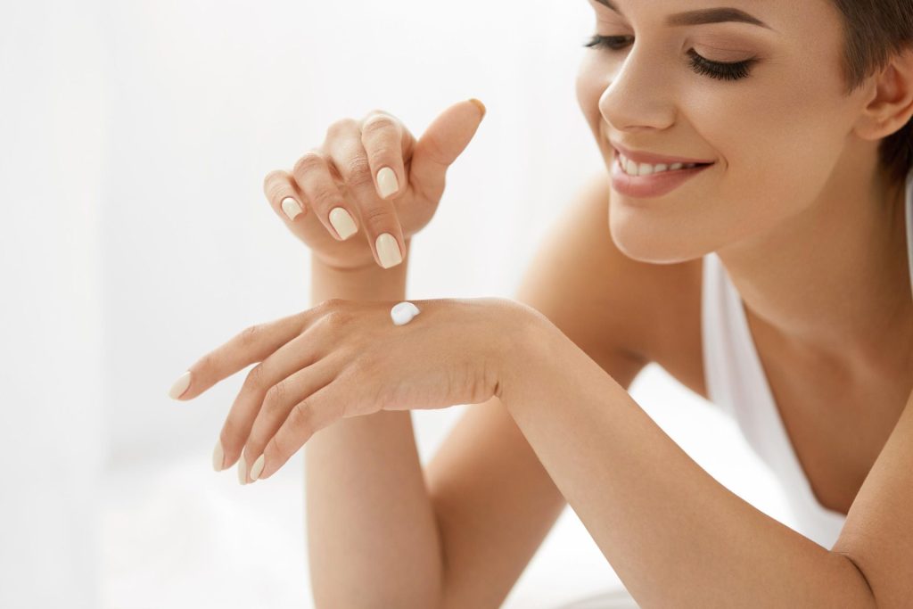 Happy woman applying cream to her hands